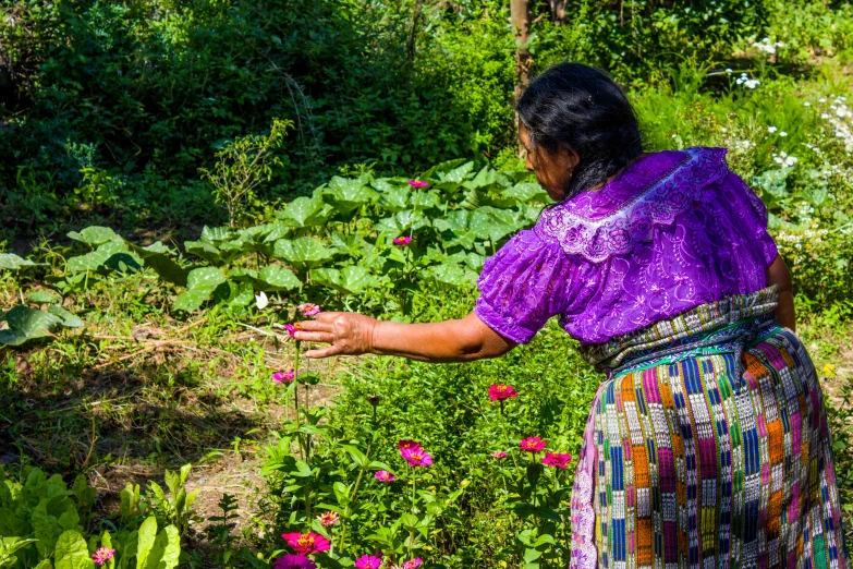 a woman is holding out her hand over flowers and plants