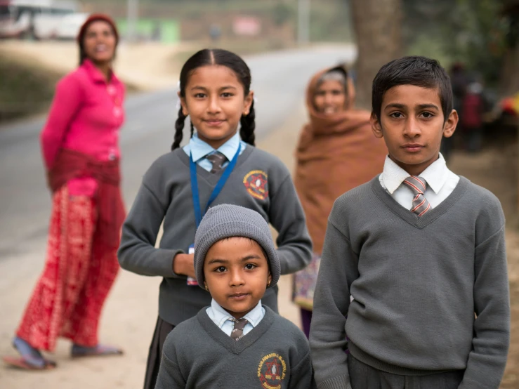 group of children wearing school uniforms on side of road