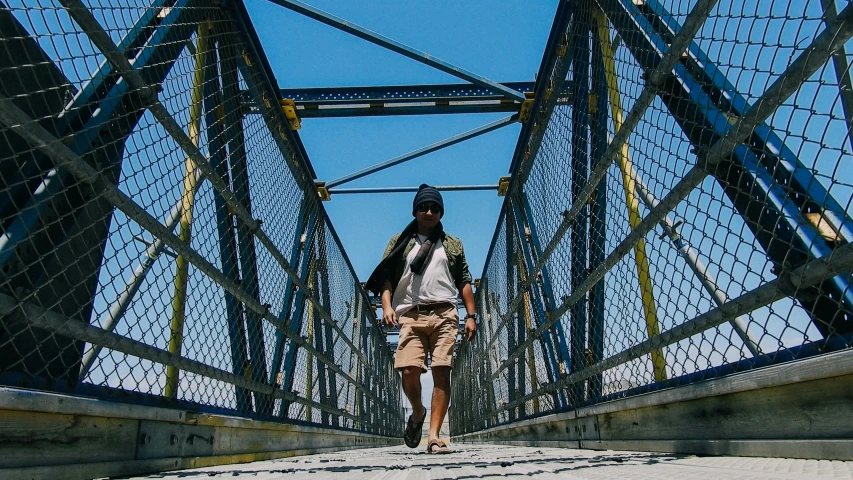 the man is walking across the pedestrian bridge