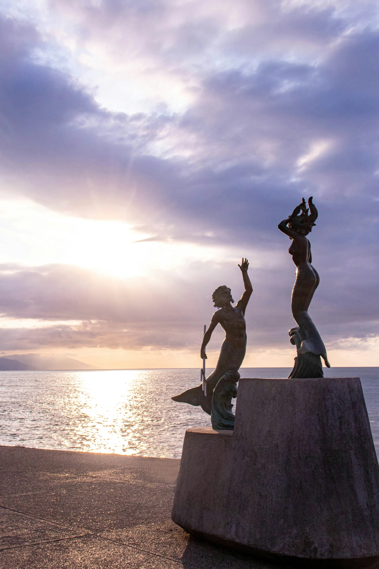 two boys playing and jumping off a sculpture in front of the water