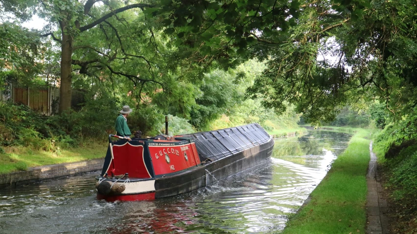 a narrow red boat traveling down a canal
