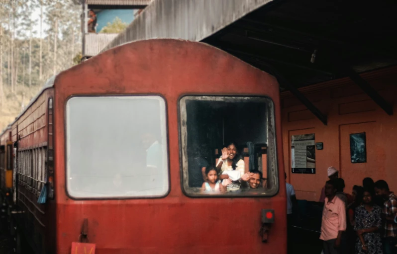 people look out the window of a train as it leaves