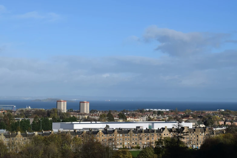 a cityscape with many large buildings, lots of trees and water in the background