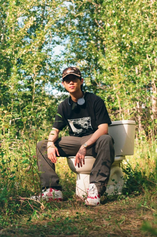 young man sitting on toilet with his head in the air