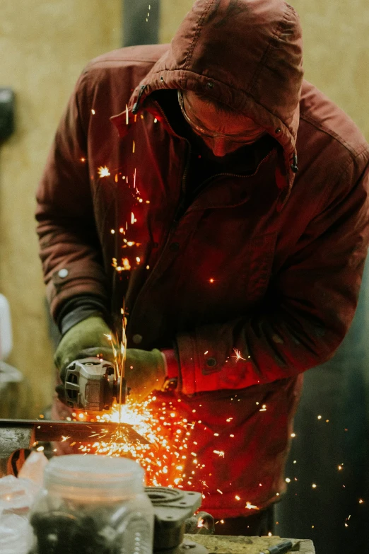 a person standing over  soing while sparks fly from the machine