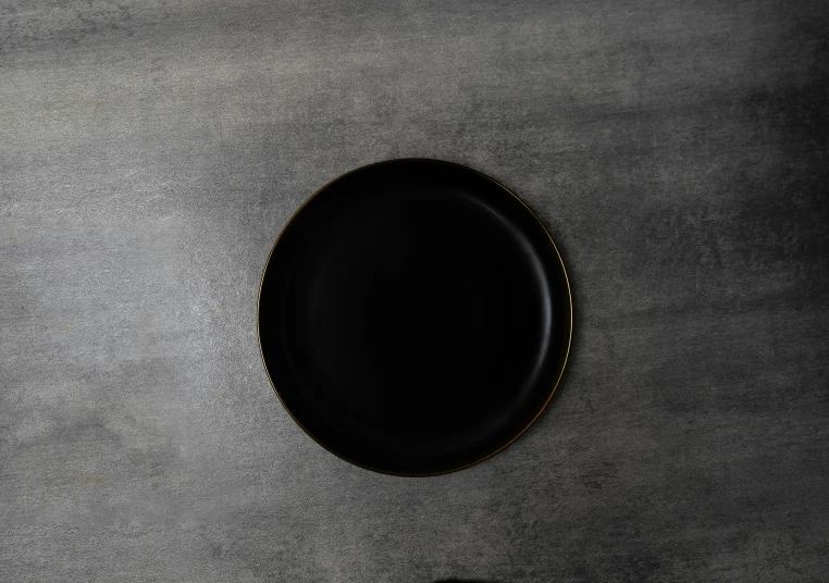 a white plate with a black rim on a gray table