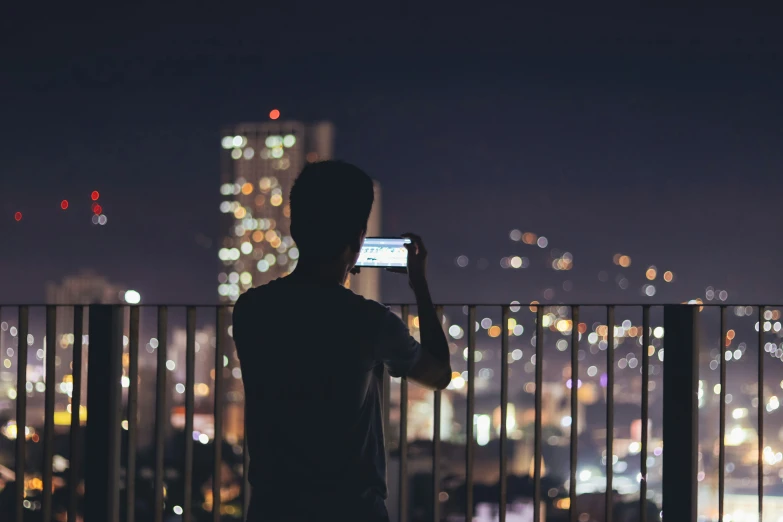 a man standing in front of a fence using a cellphone