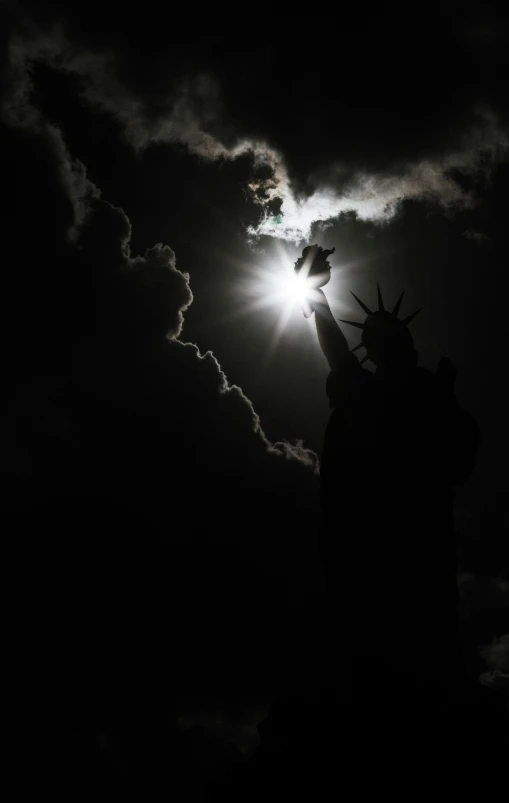 the statue of liberty is silhouetted against the clouds at night