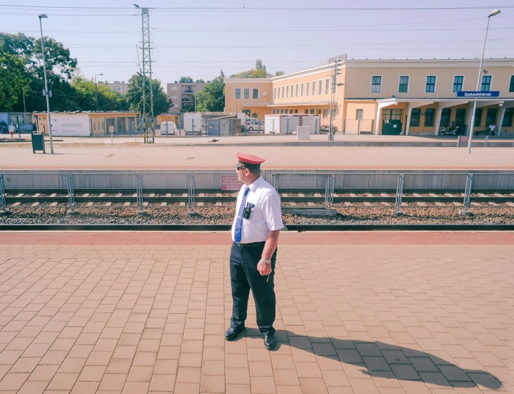 the man wearing a red hat stands next to a train