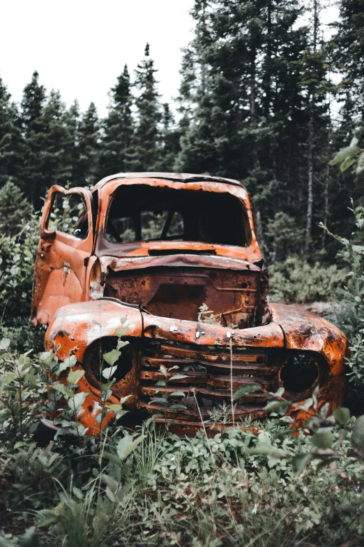 an old rusted truck in the middle of a field