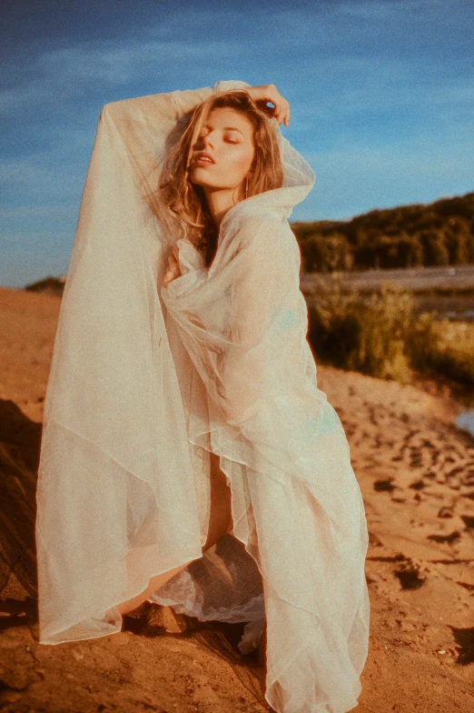 a woman wearing white clothing standing on the beach