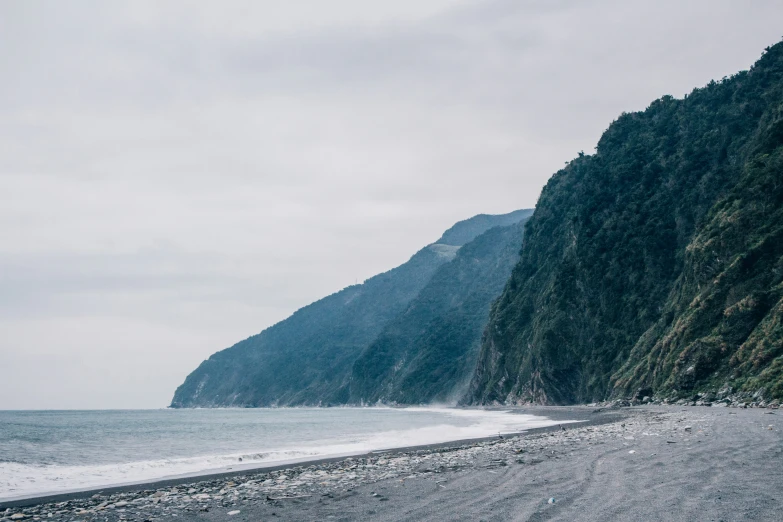 a black and white picture of a beach near a cliff