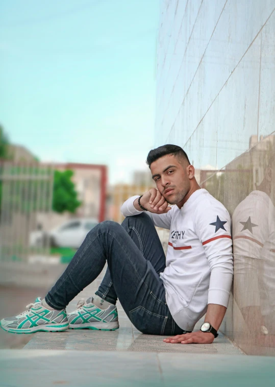 a man with black hair sitting on the side of a building