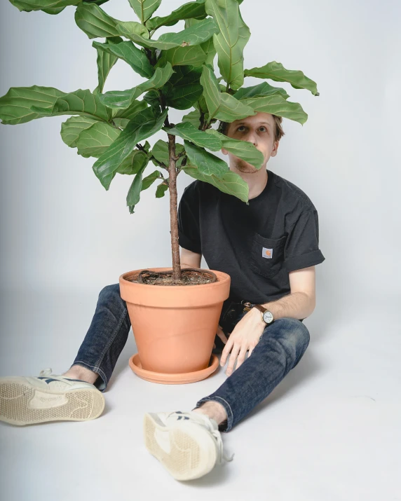 a man sitting next to a potted plant