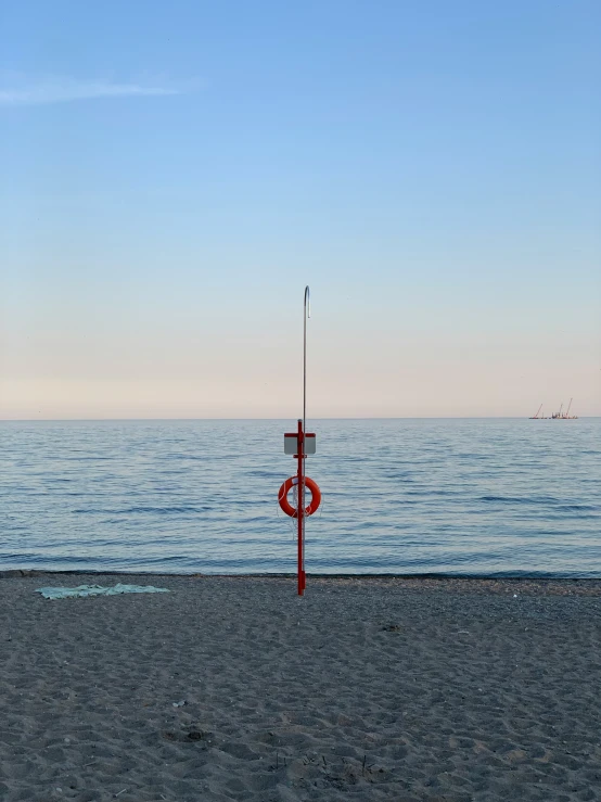 a red pole sitting on top of a sandy beach