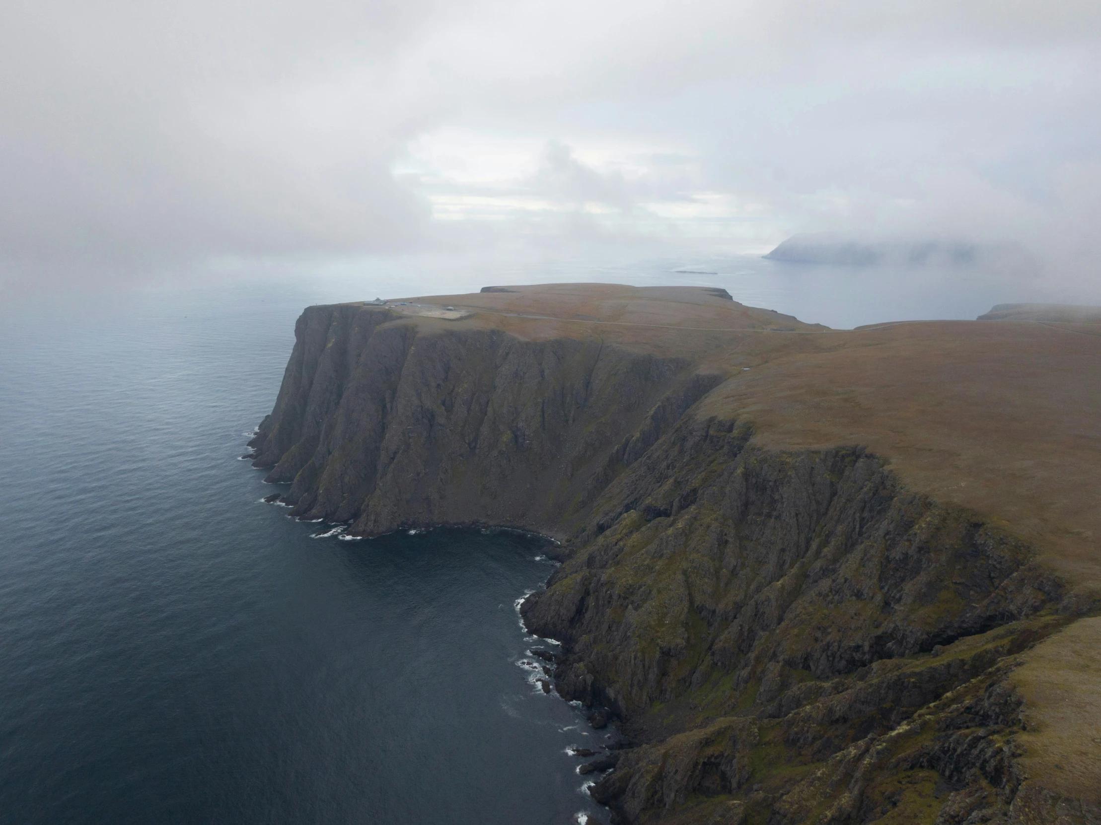 a boat that is floating in the water near a large cliff