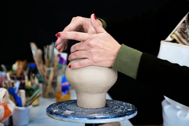 a woman holds the top of a sculpture