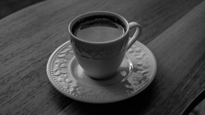 a cup on top of a saucer sits on a wooden table