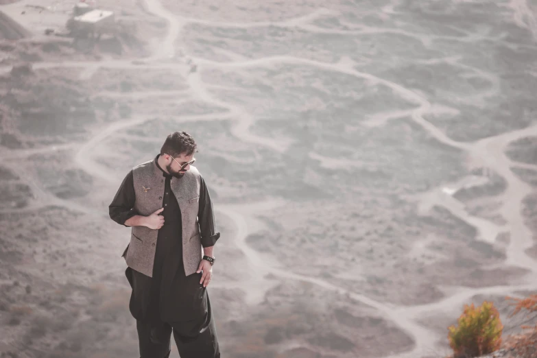 the man is standing on top of a hill near a foggy field