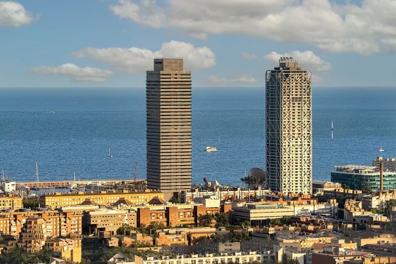 two tall buildings in the foreground with a large body of water in the background