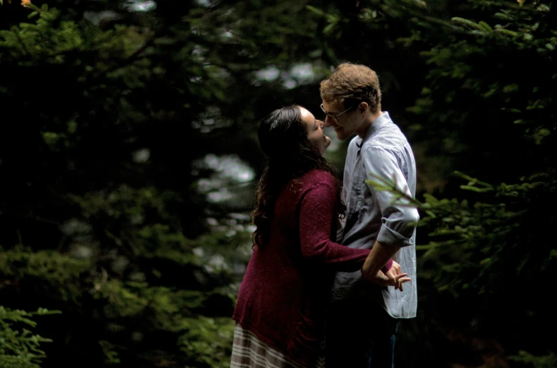 a couple is standing in the woods kissing