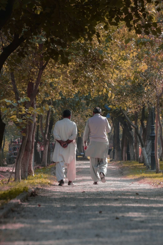 two people walk down a tree lined road