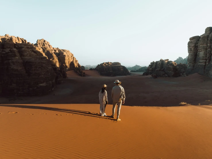 two people in their native clothing are walking in the desert