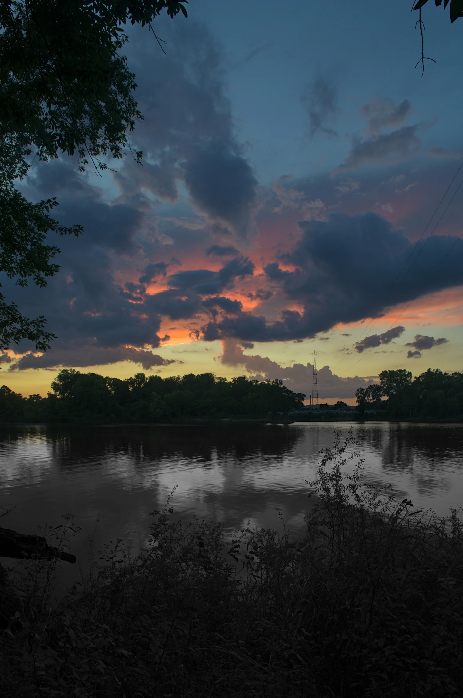 a lake that has trees around it with the sky partially obscured by clouds