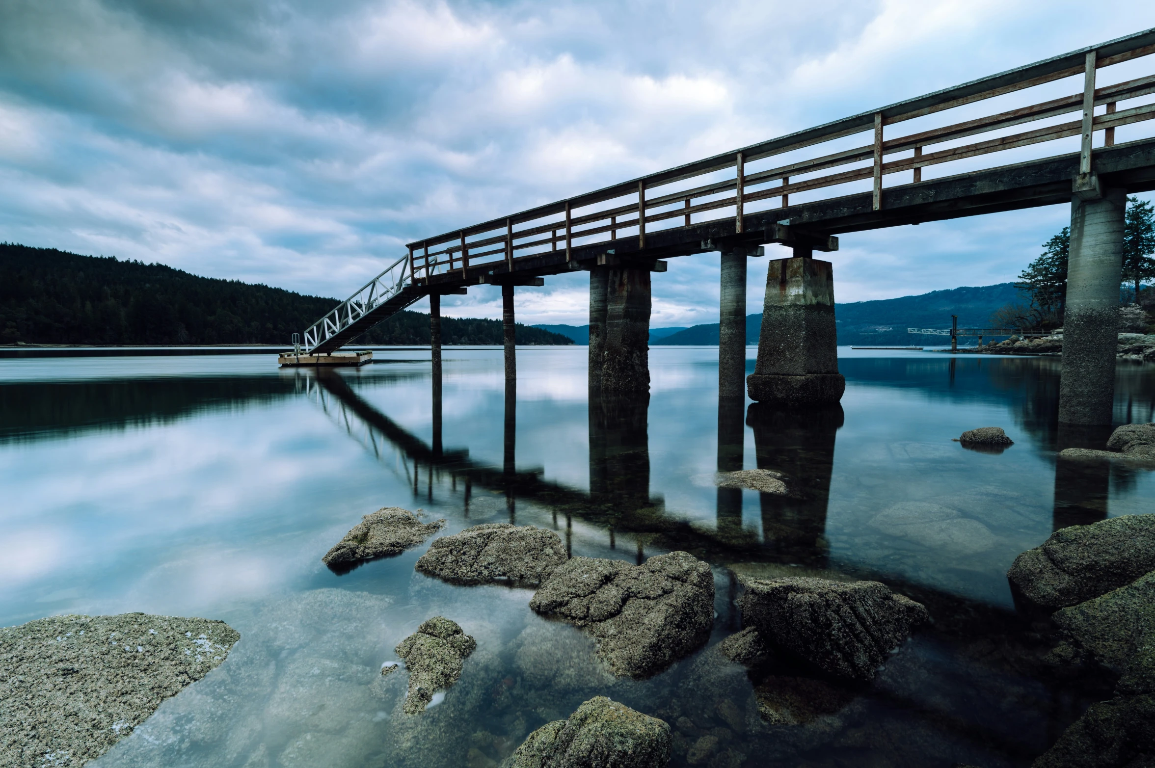 a pier is on a wide stretch of water under a cloudy sky