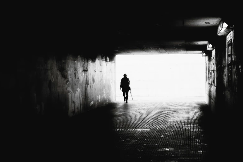 a person walking through a tunnel while holding a suitcase