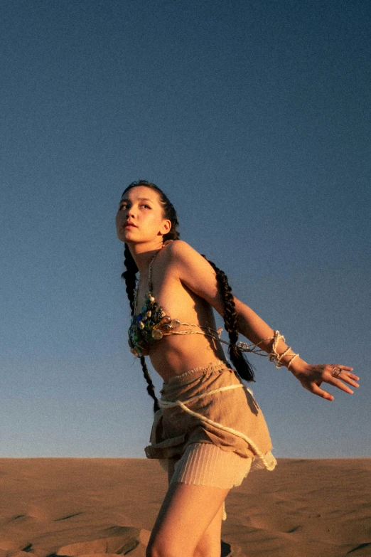 a woman stands in the middle of sand, with arms outstretched up