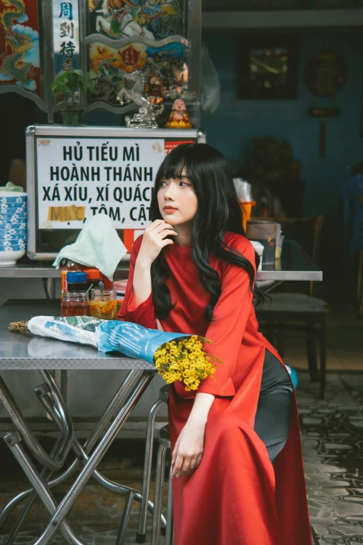 a woman in a red dress sits at a table