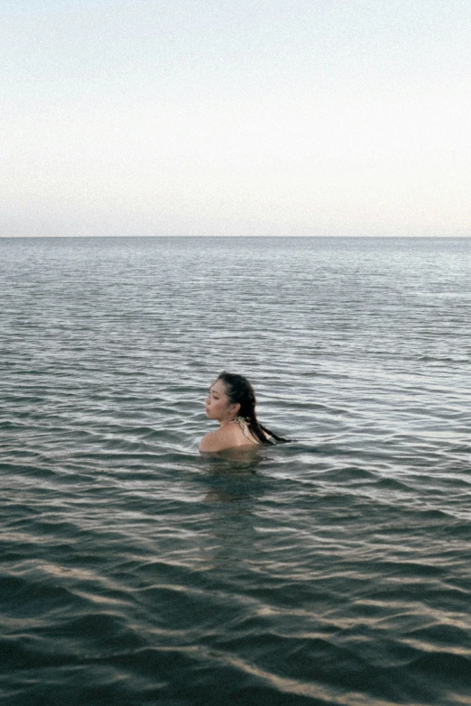 a woman swimming on top of a lake next to a boat