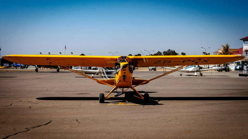 a yellow airplane sits in an open parking lot