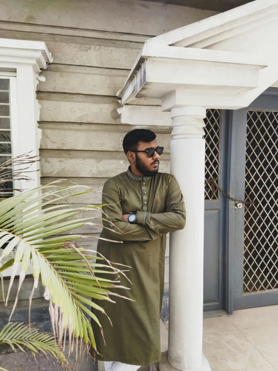 man leaning on white pillars and wearing all black