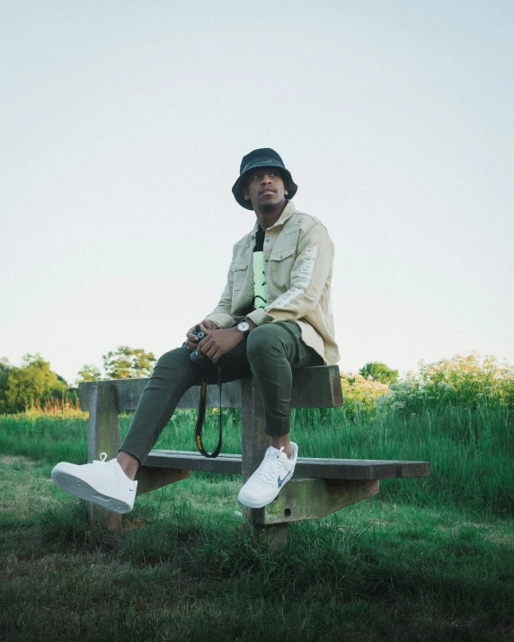 a man is sitting on a bench in the grass