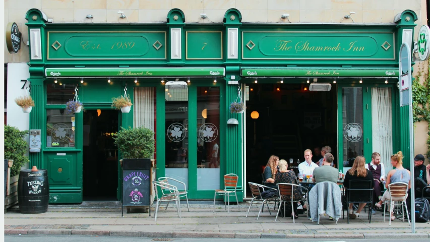 people sit at outdoor tables outside the front of a restaurant