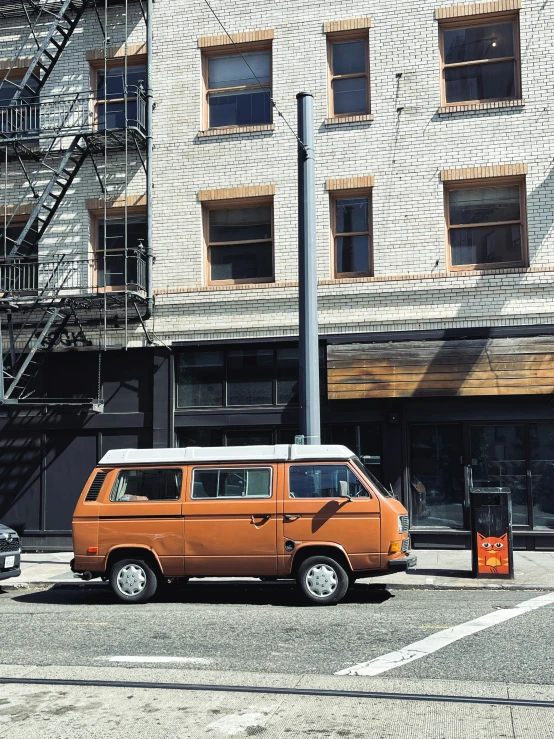 an orange van parked in front of a tall building