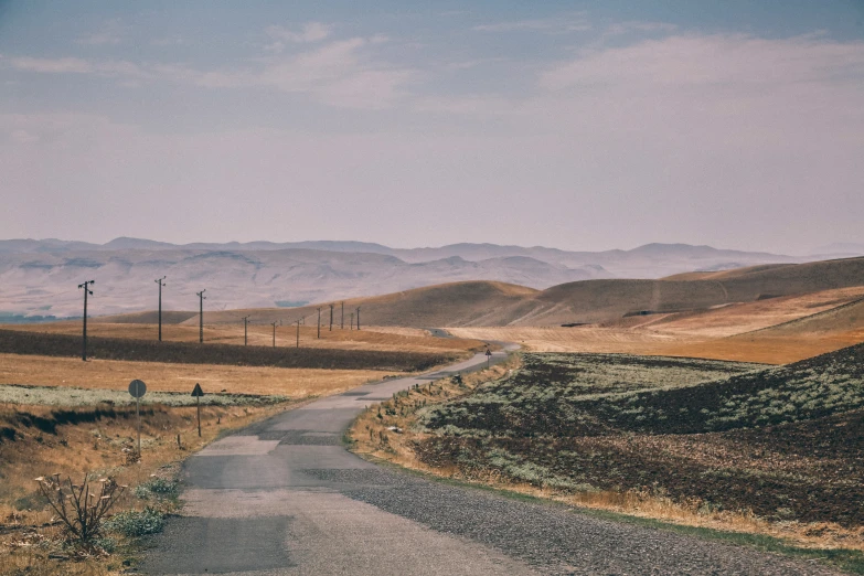 a paved road passing through a desert, leading to mountains