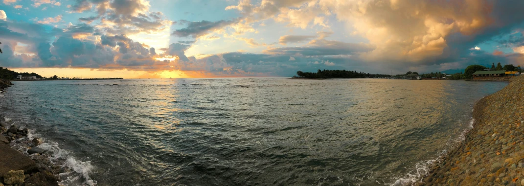 the sun shining on the water and a house near the shore