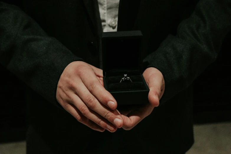 a person is showing off a ring in the palm of his hand