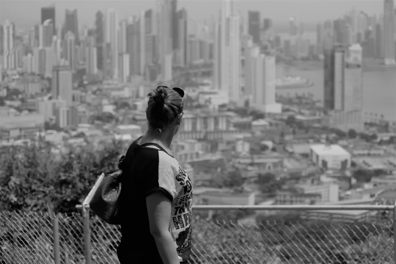 a woman looks over an urban city on a hill