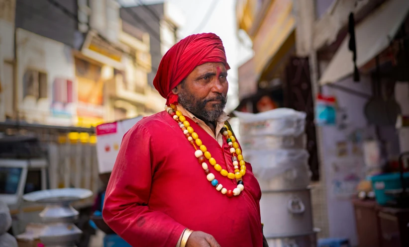 a man is wearing a red outfit and a bead of gold necklace