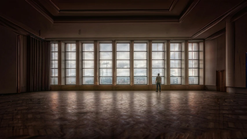 a man standing in an empty room next to several large windows