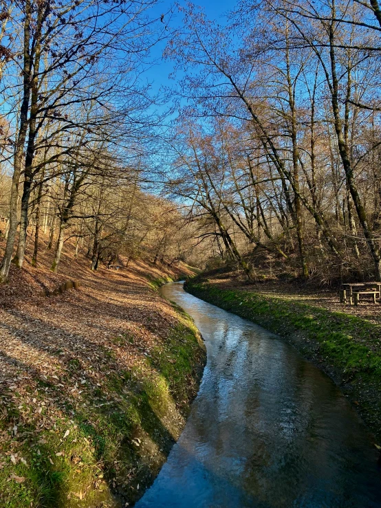 a creek running through the middle of some dry grass and trees