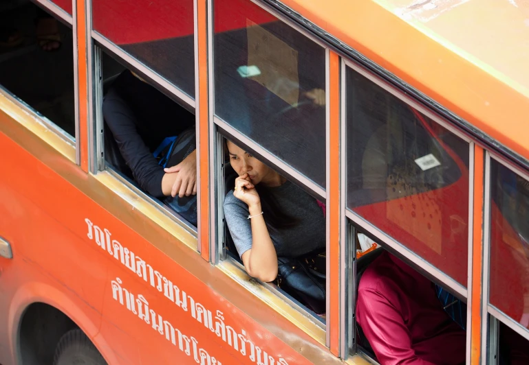 two people look out the windows on a school bus