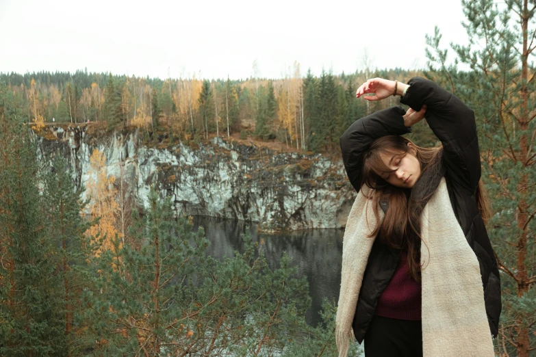 an attractive woman with long hair posing on top of a cliff