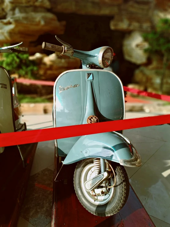 a moped is parked at the end of a red ribbon