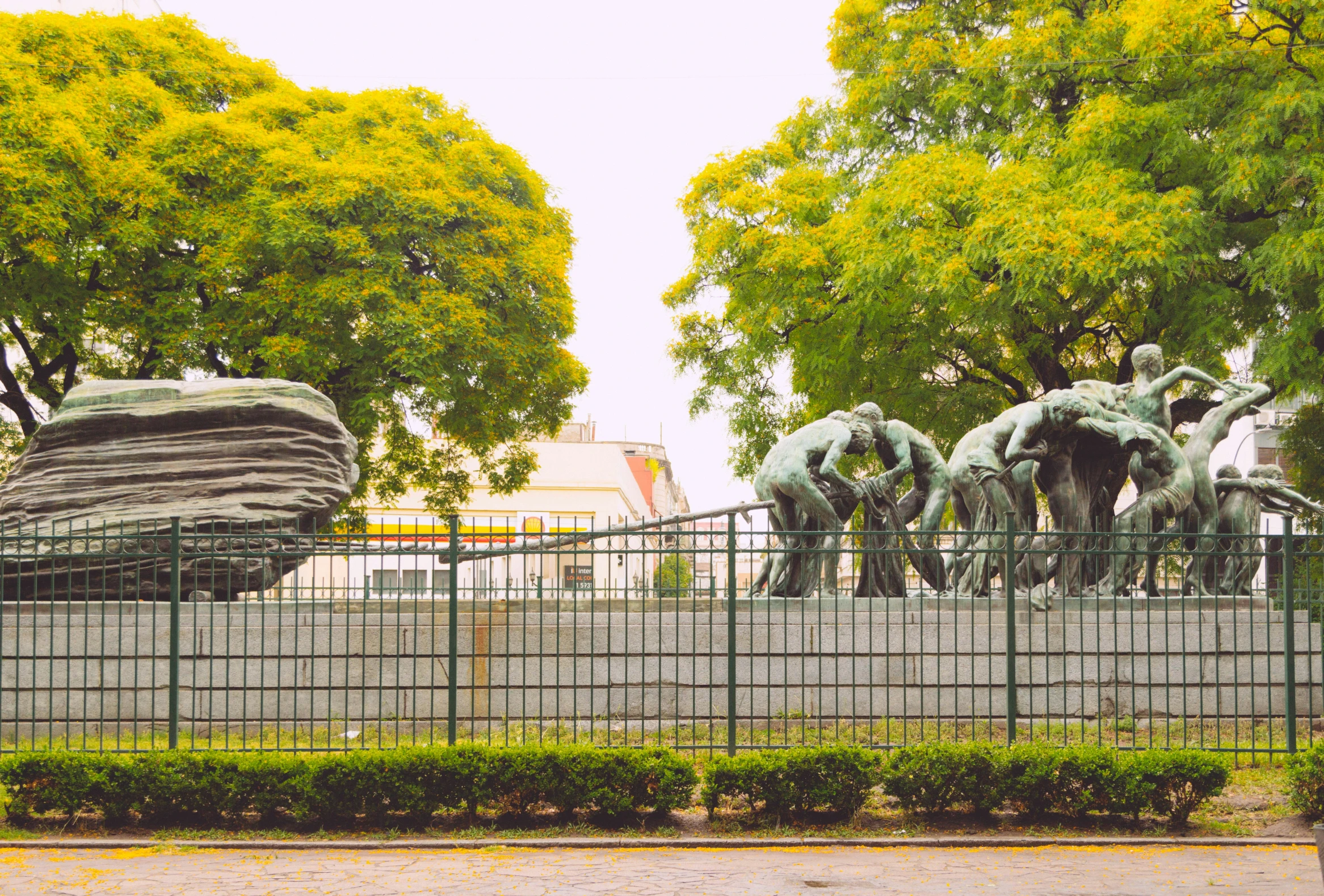 a fence with a statue in the middle of a park