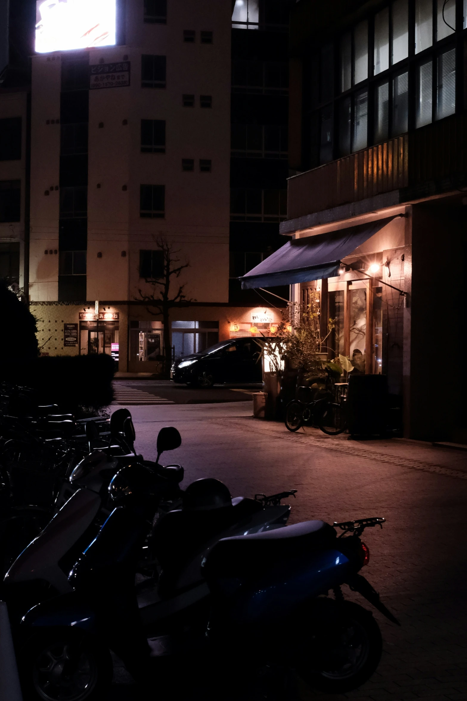 a line of parked motorcycles next to buildings at night